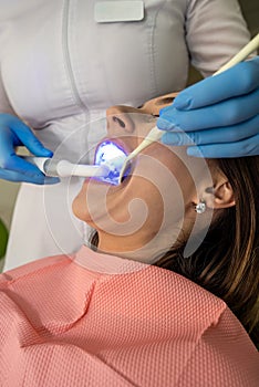 Woman patient receive procedure for teeth whitening bleaching with uv lamp