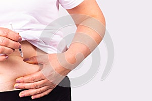 Woman patient sick with diabetes presses on the belly with the finger and injecting insulin into the abdomen using