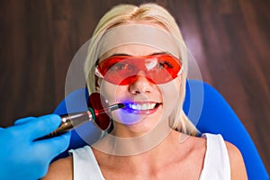 Woman patient sitting at reception with dentist and hands with tools