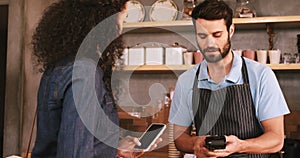 Woman paying bill through smartphone using NFC technology