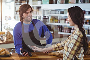 Woman paying bill through smartphone using NFC technology