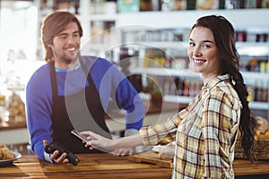 Woman paying bill through smartphone using NFC technology