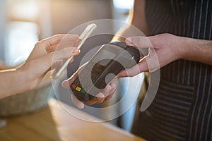 Woman paying bill through smartphone using NFC technology