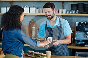 Woman paying bill through smartphone using NFC technology