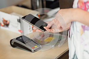 Woman paying bill through smartphone using nfc technology in cafe