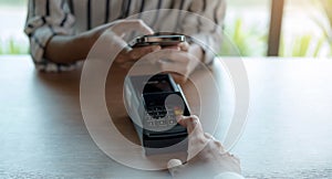 Woman paying bill through smartphone using NFC technology in a coffee. customer paying through mobile phone using contactless