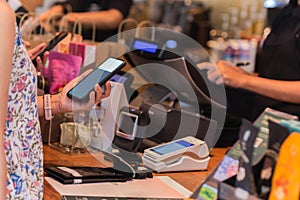 Woman paying bill through smartphone using NFC technology in a restaurant.