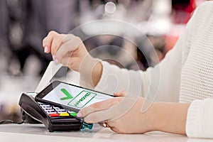 Woman paying bill through smartphone using NFC technology in restaurant, cafe, bar