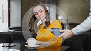 Woman paying cafe bill with credit card through PIN pad, contact less payment