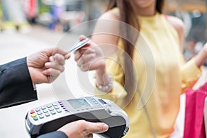 Woman paying credit card with payment terminal and cashier man