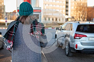 Woman paying for gasoline via credit card machine, self service petrol station without staff, rear view