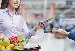 Woman paying for groceries using her smartphone