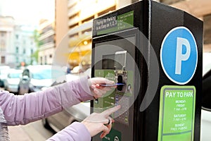 Woman is paying his parking using credit card at parking pay station terminal.