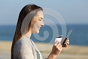 Woman paying on line with credit card on the beach