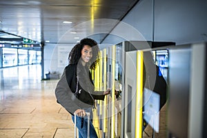 Woman paying in the parking Machine in the airport with a suitcase