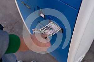 Woman paying for parking using cash at teller machine.