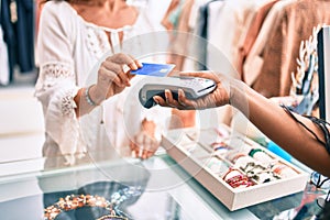 Woman paying purchase using credit card and dataphone at clothing store