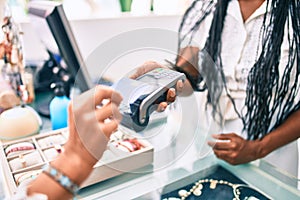 Woman paying purchase using credit card and dataphone at clothing store