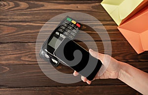 Woman paying for purchases using modern easy nfc technology, holding smartphone with blank screen, closeup