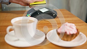 A woman pays a sweet breakfast with a contactless plastic card payment