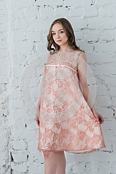 Woman in a peach dress against the white brick wall