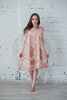 Woman in a peach dress against the white brick wall