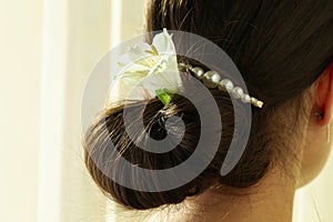 Woman with pearl hair clip and flower, close up