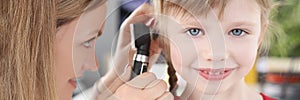 Woman pediatrician looking at eardrum of little girl using otoscope in clinic