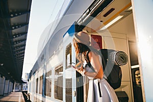 Woman peeking out train. Woman railway station. Young happy woman pulling face out train door looking for somebody