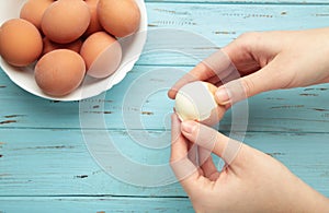 Woman peeling boiled egg on wooden blue background