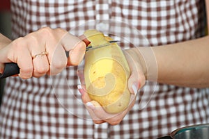 Woman peeling potatoes closeup