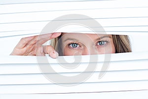 Woman peering through roller blind