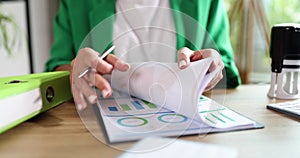 A woman with a pen flips through documents