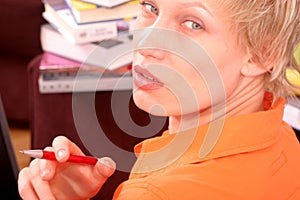 Woman with pen in hand and books