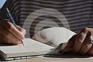 Woman with pen in hand, writing in a journal photo