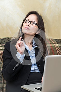 Woman with pen and laptop on sofa