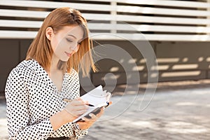 Woman with pencil writing in notebook working outdoors