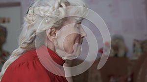 Woman pensioner with long grey plait plays music in room