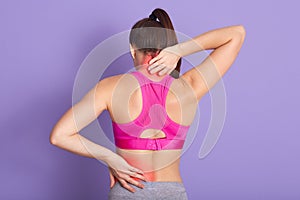 Woman with perfect body having painful muscle injury in lower back and neck. Fitness girl sport girl with sports injury posing