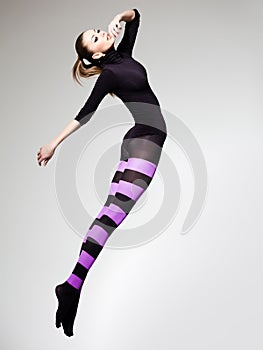 Woman with perfect body jumping dressed in purple striped tights and black top