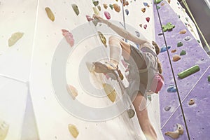 Woman with perfect fit body training on a climbing wall in sport hall, ready to workout.