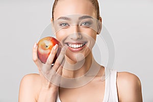 Woman With Perfect Smile Holding Apple Posing On Gray Background