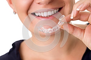 Woman with perfect teeth holding invisible braces