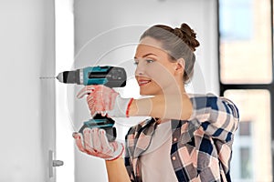 woman with perforator drilling wall at home