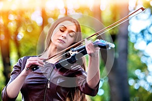 Woman perform music on violin park outdoor. Girl performing jazz .