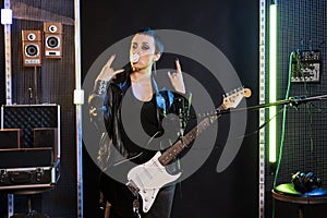 Woman performer blowing bubble gum while posing in studio doing rockstar gesture