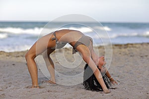 Woman performing a back bend on the beach