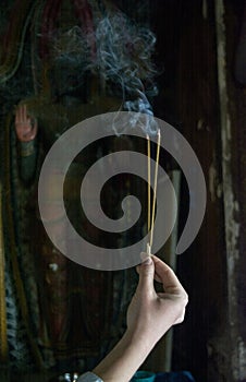 Woman performing budhist ritual using incense sticks in the temple