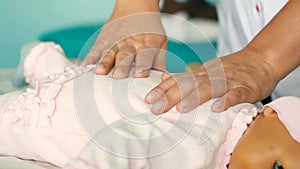 Woman performing CPR on baby training doll with one hand compression