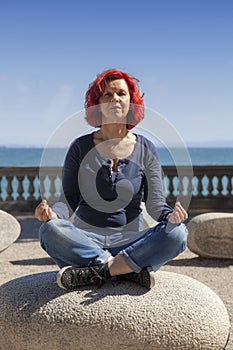 Woman performing joga on energy stones near sea coast